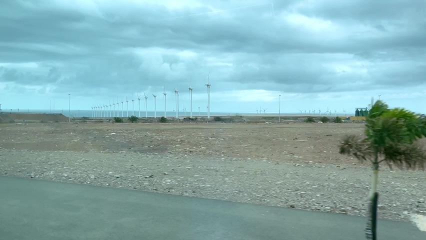 Wind turbines in a row spinning by the sea in Arinaga, Gran Canaria. Renewable clean energy farm view from car, sustainability, eco friendly resources concepts