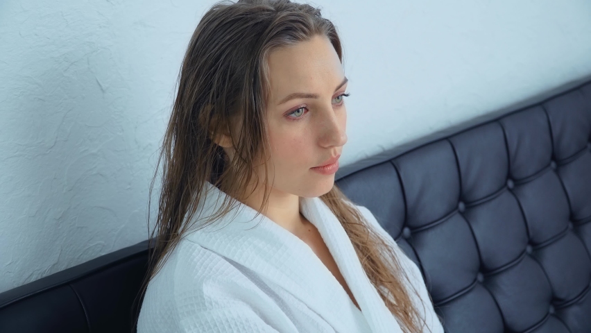 Young woman in bathrobe with wet hair waiting in clinic. Concept of body care and rehabilitation of spiritual peace