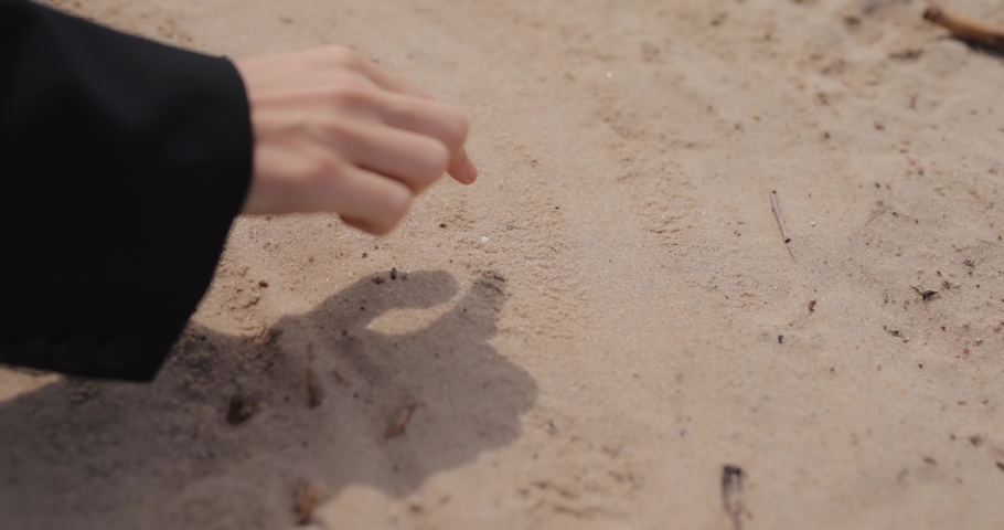 Woman hand drawing heart on the beach closeup