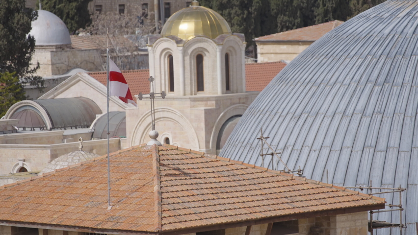 Flag waving on top of the roof of the Church of the Holy Sepulchre in Old Jerusalem. Slow motion.