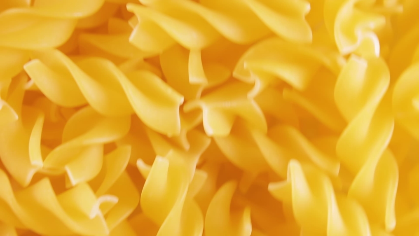 Uncooked Fusilli Pasta - Top View. Fat and Unhealthy Food. Dry Spiral Macaroni, Moving Background. Italian Culture and Cuisine. Raw Golden Pasta Pattern. Upward Movement