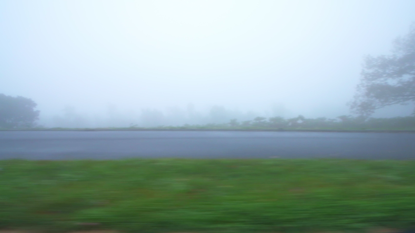 Side point of view pov vehicle driving at Blue Ridge Parkway road, Virginia at autumn foliage Appalachian mountains in thick fog mist weather and clouds