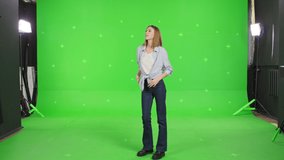 Young woman dancing on a green screen background. Girl makes a gesture with her hands as if swipping the page to the side . Chroma key