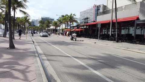 Ft. Lauderdale, Florida - November, 2021:  A group of motorcycles seen riding between cars on a palm tree lined street 
