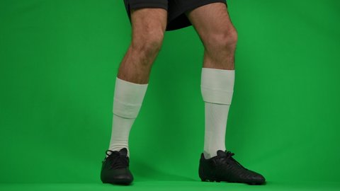 Unrecognizable footballer dribbling ball on green screen leaving. Young confident professional Caucasian sportsman running away with soccer ball at chromakey background template