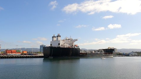 Oakland, CA - April 17, 2022: 4K HD video driving past U.S. Naval Ship JOHN GLENN docked at the port of Oakland.
