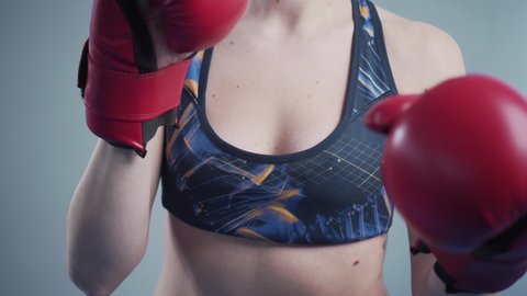 Beautiful sporty woman posing wearing boxing gloves. Attractive sportswoman boxer posing for a photo shoot in the gym. Cheerful fitness woman posing with boxing gloves during the photo session