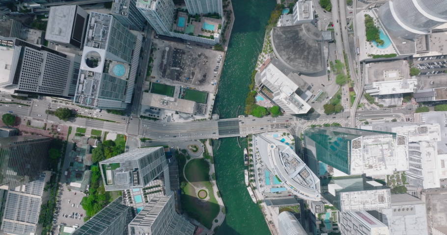 Birds eye view of futuristic urban borough with tall buildings and skyscrapers. Multilane road bridge above turquoise water in river. Miami, USA