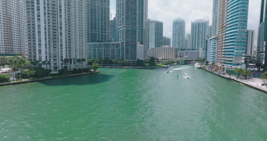 Modern high rise luxurious downtown buildings along river. Motorboats driving on water surface. Miami, USA