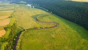 The winding river flows through a picturesque green valley. Footage from a bird's eye view. Location place Ukraine, Europe. Cinematic drone shot. Filmed in UHD 4k video. Discover the beauty of earth.
