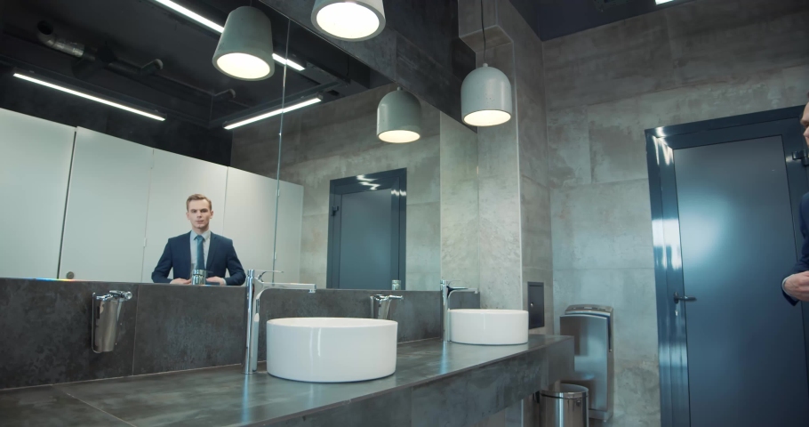 Business man in office bathroom. Stressed manager using restrooms, washroom and lavatories while looking at receding hairline. Male beauty in public toilet with businessman checking hair for loss