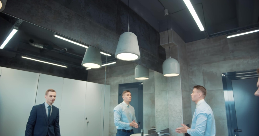 Two business man in office bathroom. Stressed manager using restrooms, washroom and lavatories while looking at receding hairline. Male beauty in public toilet with businessman checking hair for loss Royalty-Free Stock Footage #1089396835