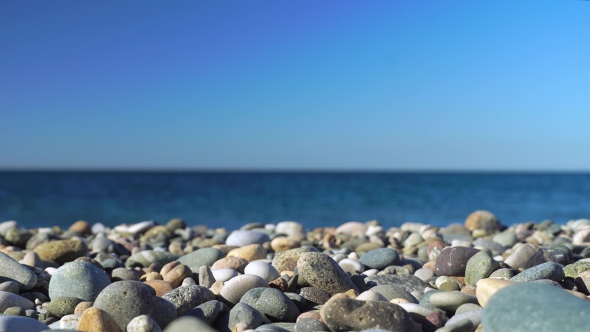 Handmade stone tower on the sea beach. Close-up of a pile of balanced pebbles on the beach. A woman