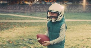 Family fun outdoors, Cheerful happy child in helmet playing American football outdoors in sunny day at public park. Family sports weekend. 4K video.