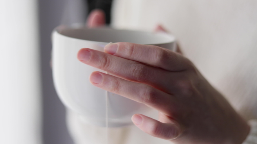 Woman's hands holding a big white cup of tea | Shutterstock HD Video #1089400173