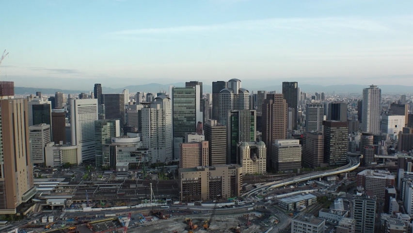 UMEDA, OSAKA, JAPAN : Aerial high angle sunset view of CITYSCAPE of OSAKA. View of buildings and street around Osaka and Umeda station. Wide view time lapse shot, dusk to night. Urban city concept. Royalty-Free Stock Footage #1089401229
