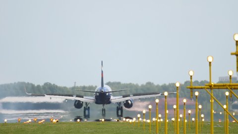 AMSTERDAM, THE NETHERLANDS - JULY 27, 2017: Aeroflot plane raised flaps, braking after landing at Schiphol Airport, Amsterdam. Runway and landing lights at the airport. Travel concept