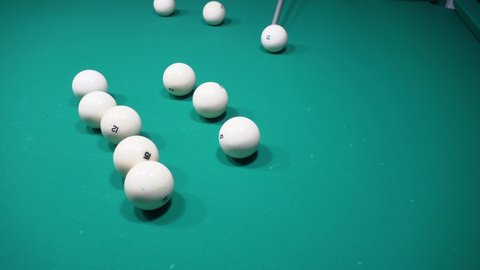 A sports game of billiards, pool or snooker on a billiard table with a green cloth.Hitting billiard balls with a cue. Cue kick.Participate in games and competitions,score a goal in the pocket in match