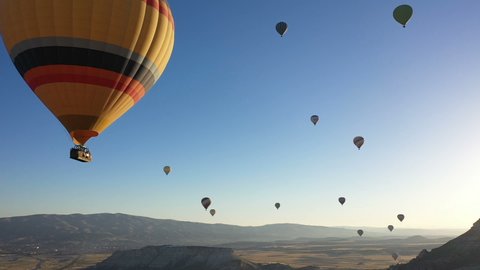 Colorful hot air balloons are flying in the blue sky. drone follows hot air balloons. beautiful blue sky background. Hot air balloons in Cappadocia