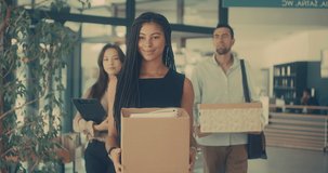 Young business people of mixed-races with boxes come back to office. Colleagues going to work in modern workspace, teamwork together. 4k Slow motion video.
