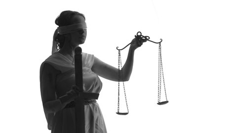 Goddess of justice raises the scales. White woman blindfolded on white background in studio, closeup, side view. Concept of legal justice