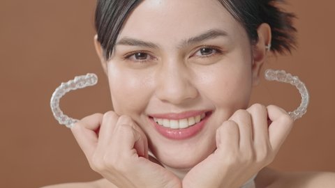 A young woman with beautiful teeth is holding Invisalign, healthy dental concept 