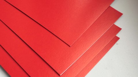 4k video, close-up of a stack of red paper rotating on a white background.