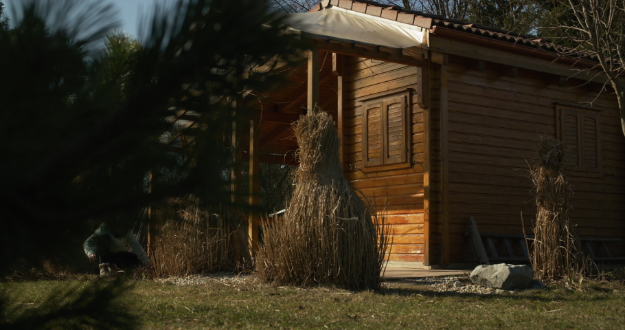 woman working in front of a garden cottage on a sunny spring day