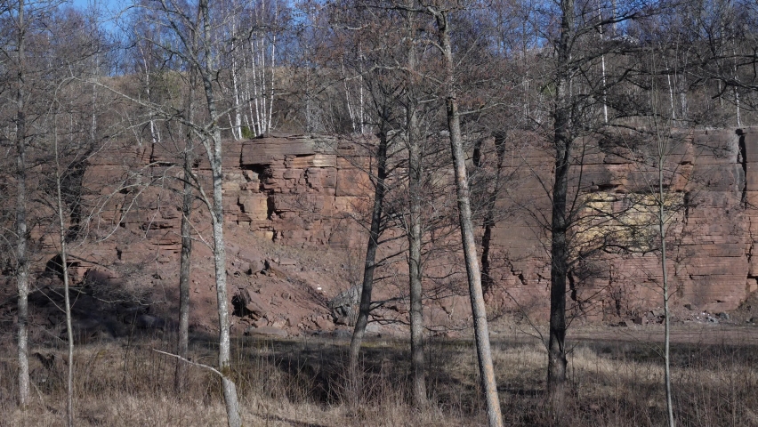 Red limestone quarry from Kinnekulle, hidden by trees.