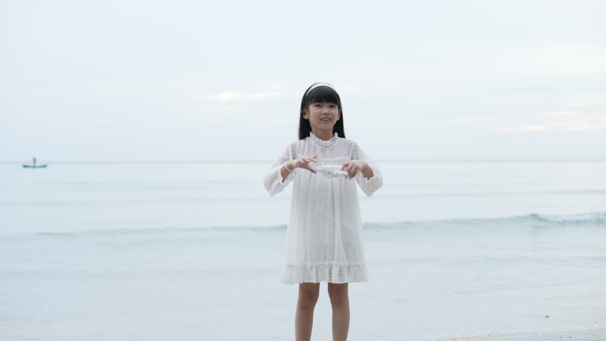 Holiday concept of 4k Resolution. Asian girl playing toy plane on the beach. fun of childhood.