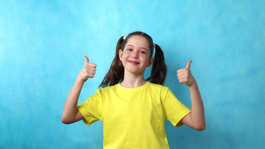 Beautiful little girl smiling joyfully and looking happy, feeling carefree and positive, pointing fingers to the side, looking at the camera