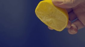 Hand squeezing half of lemon on black background. Hand squeeze lime with lime drop. Pressing and squashing lemon juice on hand in studio 4K video footage. Represent sour and refreshing drink menu.