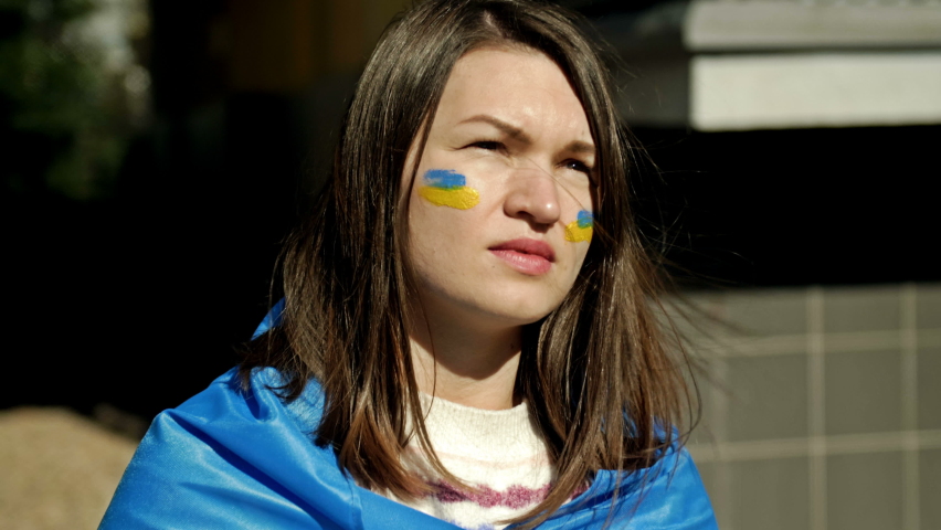 Portrait of a woman with a Ukrainian flag on his shoulders. Protest against the war in Ukraine and Russian aggression.
