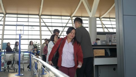 HONG KONG - JANUARY 20, 2020: Airport worker checks travellers with luggage after flight at the Hong Kong airport