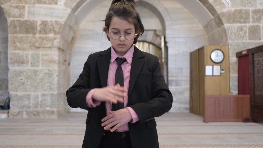 Little boy who starts prayer by saying takbir, little boy wearing a suit praying in the mosque, muslim boy worshiping god according to islamic rules