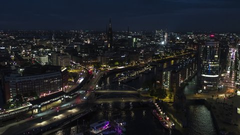 Establishing Aerial View Shot of Hamburg De, Mecklenburg-Western Pomerania, Germany at night evening, view from river, super clear image, push in over bridges