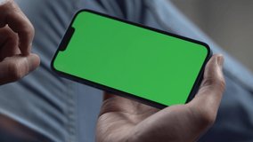 Man Using Smartphone in Horizontal Mode with Green Mock-up Screen. Internet Social Networks Browsing News, Financial Reports