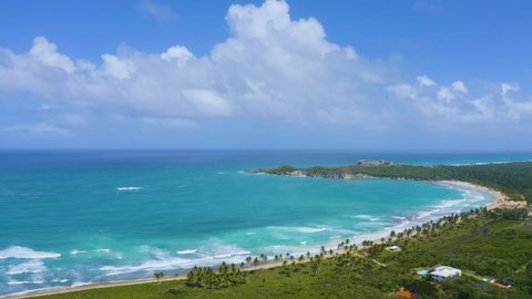 Blue lagoon at the sandy palm beach. Summer, sea, palm trees and sand on the tropical coast. Sunny day on a beautiful green peninsula. White fluffy cloud in the blue sky. Travel and vacation at sea.