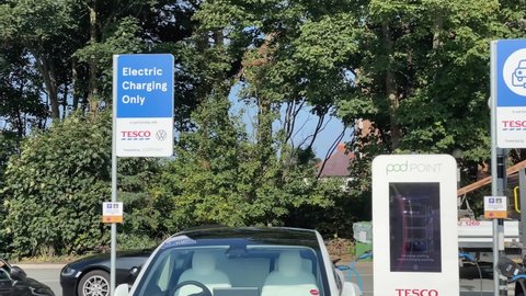 WIRRAL, MERSEYSIDE, ENGLAND - SEPTEMBER 15 2021: Electric cars charging with electricity for free at Tesco supermarket. Volkswagen and Tesco deliver the UK’s largest retail EV charging network.