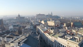 Krakow old town. aerial video footage. camera moves over the roofs of houses of the central street of Krakow. in the distance is Wawel castle on hill. morning atmospheric fog. Poland