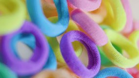 vertical screen Format multicolored rubber bands on the blurred background. circular textile hair elastic, 4K selective focus footage
