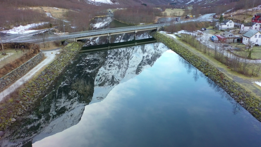 Bridge with road E16 crossing Gudvangen river Norway - Forward moving aerial above naeroy valley river with beautifu mountain reflections in water surface