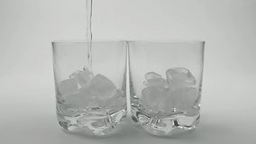 Two glasses with ice are filled with clean water from a bottle, slow motion - Powered by Shutterstock - Get 15% off with code: PIKWIZARD15