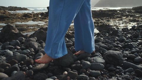 Two beautiful woman walk along the volcanic beach of Tenerife. Close-up shot of feet walking on the beach