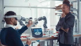 Robot Arm Software Design Research Facility: Black Female Engineer Look at Laptop and Supervising Design Specialist Using VR Headset and Controllers. VR Technology for Industrial Design, Development - Powered by Shutterstock - Get 15% off with code: PIKWIZARD15