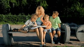Mom and her kids reading a book outdoors