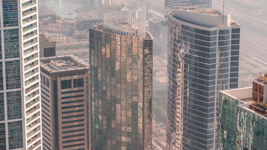 Modern buildings with colorful stained glass windows with reflections early morning in Dubai Media City timelapse, United Arab Emirates. Aerial view from above with traffic