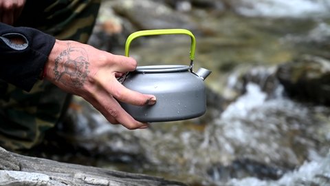 Rudraprayag, India - July 16 2020: Refilling water from a waterfall during camping in the mountains into the wild cooking utensil during outdoor trekking gear సంపాదకీయ స్టాక్ వీడియో