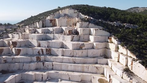 Marble quarry real time footage from above. Ledges of excavated marble stone material at Mediterranean region of Mersin, Turkey. Aerial view