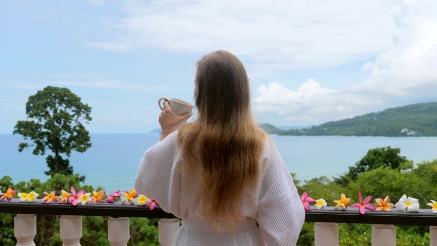 Luxury travel, romantic vacation on tropical villa for honeymoons. Woman drinking morning coffee on terrace with blue sea view. Tropical vacation in resort. | Shutterstock HD Video #1089451871